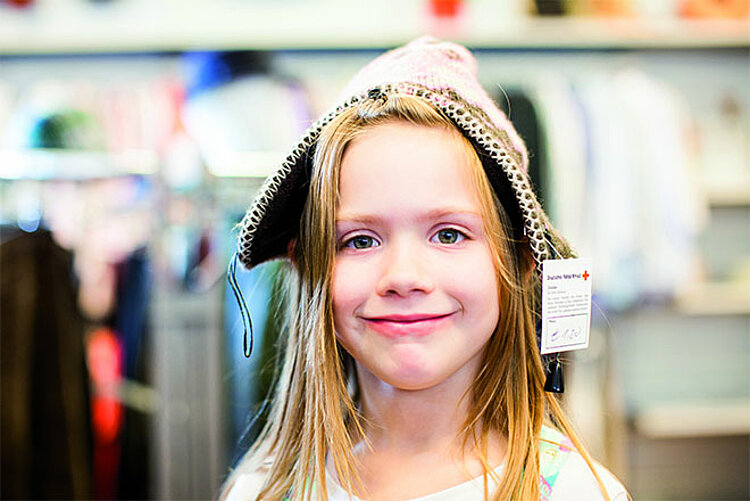 Kleines Mädchen freut sich über Mütze aus DRK Kleiderladen