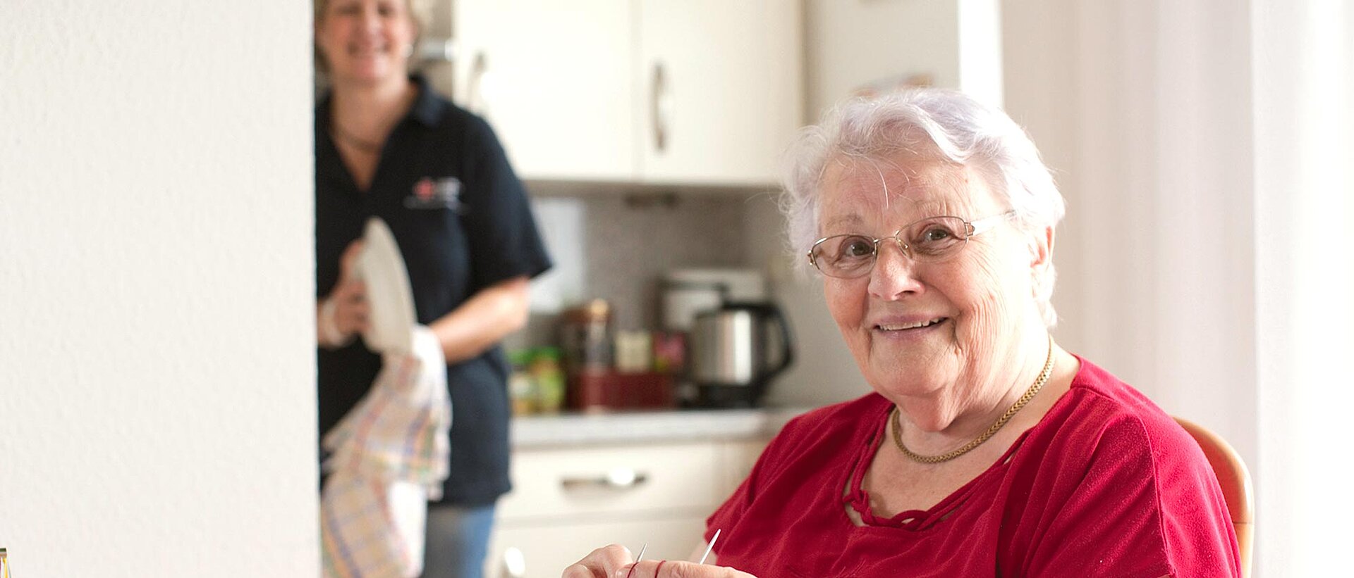 Pflegerin trocknet Geschirr bei Seniorin