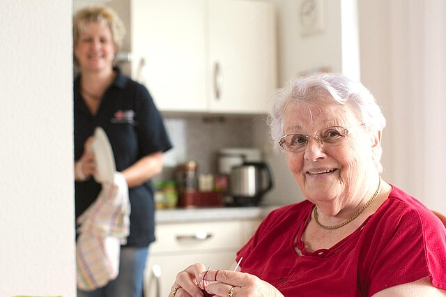 Pflegerin trocknet Geschirr bei Seniorin