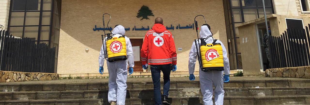 Drei Helfer des Roten Kreuzes mit Desinfektionssprühern gegen die Ausbreitung von Corona im Libanon