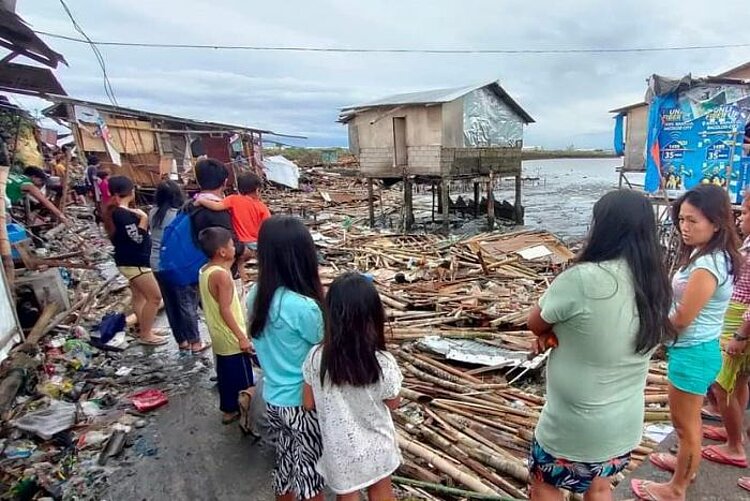 Menschen blicken auf Zerstörungen nach Taifun Rai auf den Philippinen