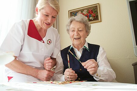 Altenpflegerin mit Seniorin an einem Tisch