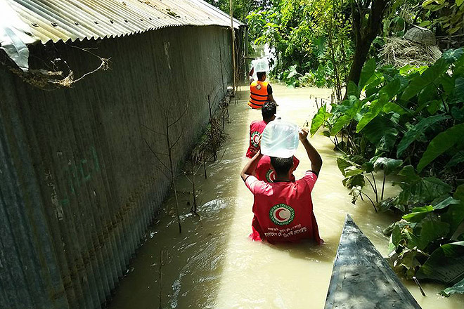 Helfer transportieren Hilfsgüter in einem überfluteten Dorf