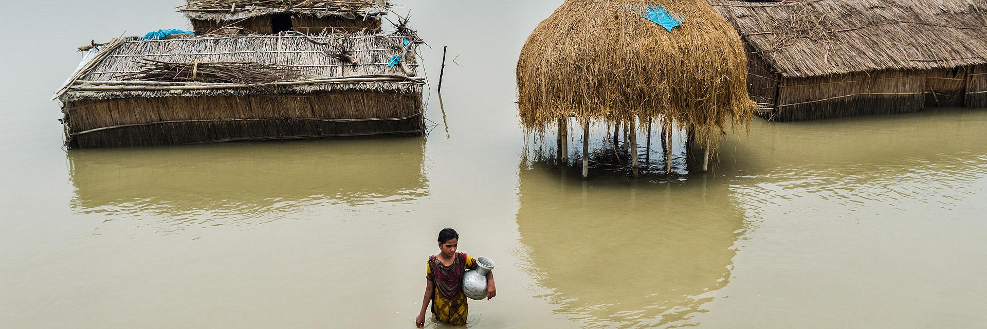 Eine Frau in einem überfluteten Dorf in Südasien