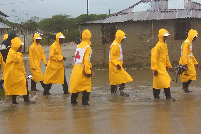 Rotkreuzhelfer auf Haiti gehen über eine überschwemmten Straße