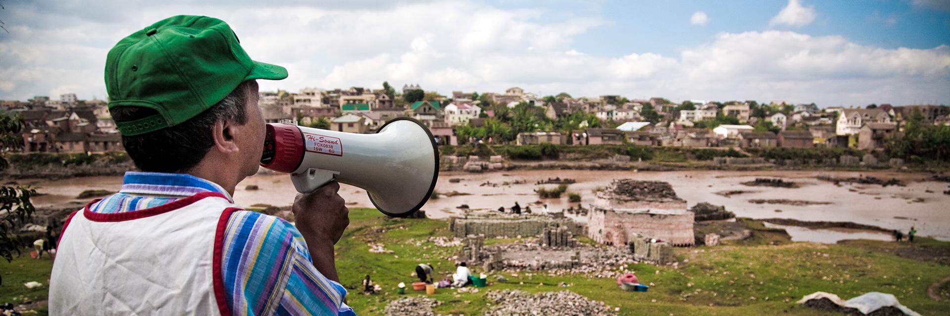 Mann in Madagaskar mit Megafon vor einem Flussufer