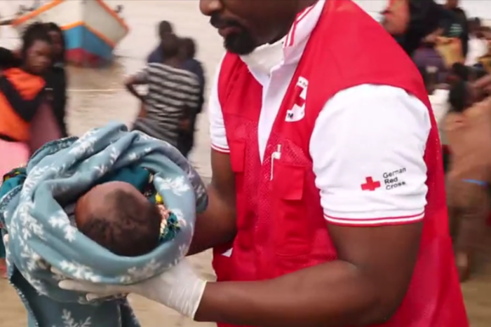 Rotkreuz-Mitarbeiter evakuiert ein Baby