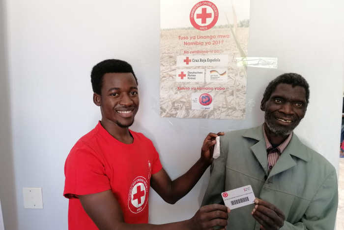 Soforthilfe in Namibia: Namibischer Rotkreuzhelfer überreicht eine Geldkarte an einen namibischen Kleinbauern