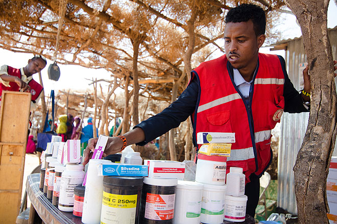 Foto: Rothalbmond-Helfer sortiert Medikamente auf einem Tisch in der somalischen Hütte