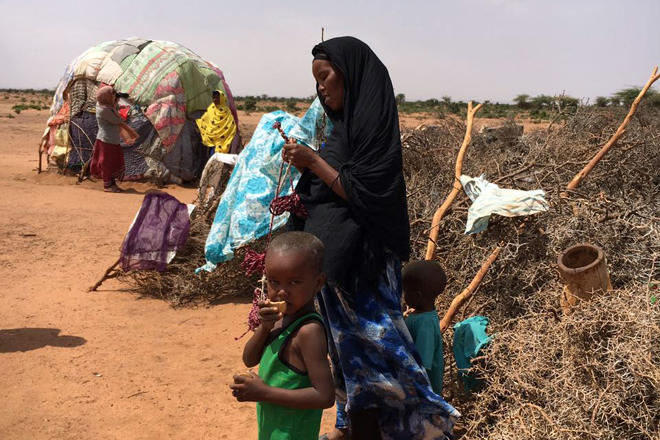 Foto: eine somalische Frau mit ihren Kindern vor ihrer Hütte
