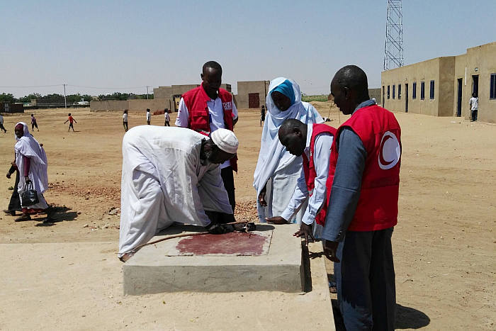 Mitarbeiter des Sudanesischen Roten Halbmonds inspizieren ein Wasserreservoir