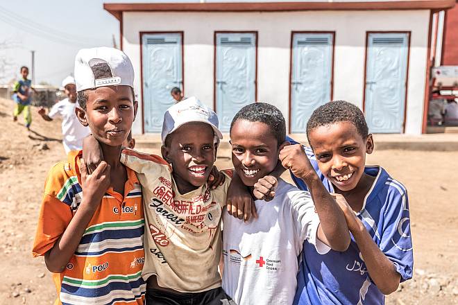 Foto: Vier somalische Jungen lachen vor neuen Latrinen.