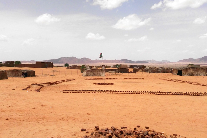 Foto: sandiges Land mit kleinen Hütten, wo eine Schule entstehen soll