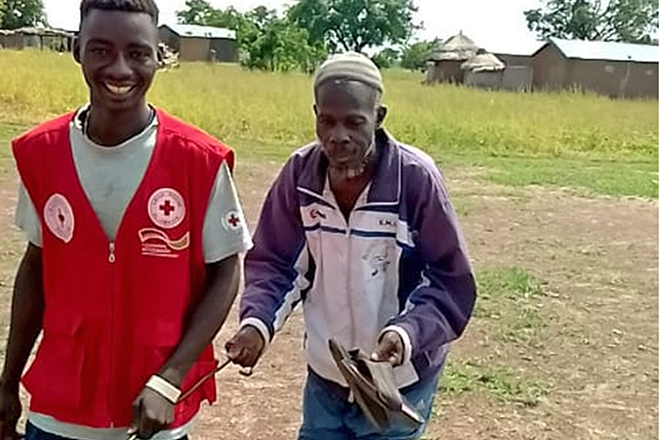 Portrait eines Rotkreuzhelfers mit Hilfsempfänger in Togo