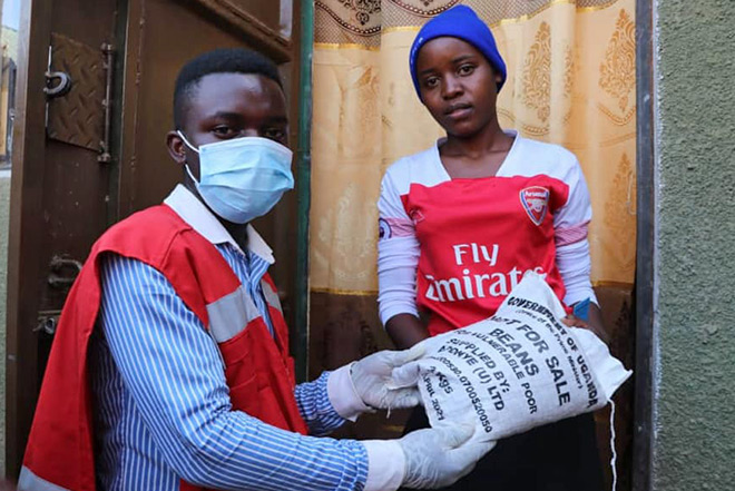 Ugandischer Rotkreuzler übergibt Bohnensack an junge Frau