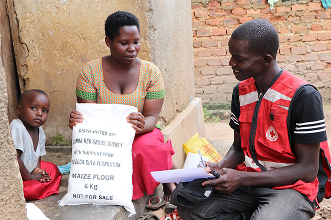 Rotkreuzler überreicht Frau in Uganda Nahrung