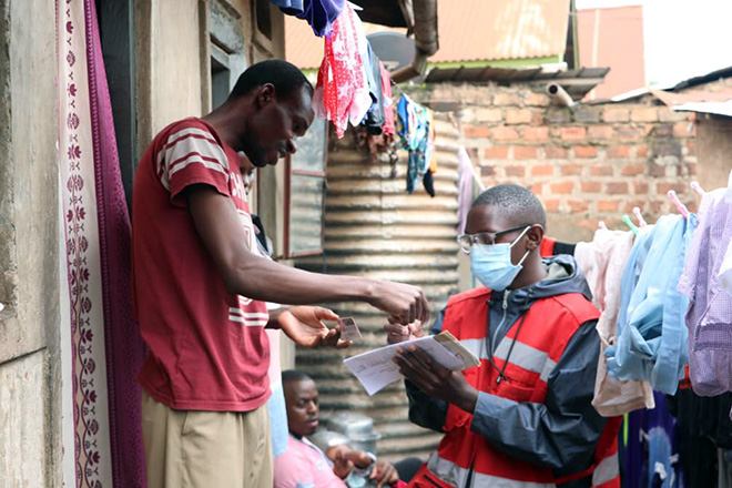 geflüchteter Mann in Uganda im Gespräch mit Rotkreuzhelfer