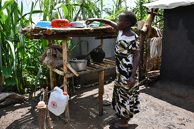[Translate to Englisch:] geflüchtetes Mädchen in Uganda an einer provisorischen Außenküche