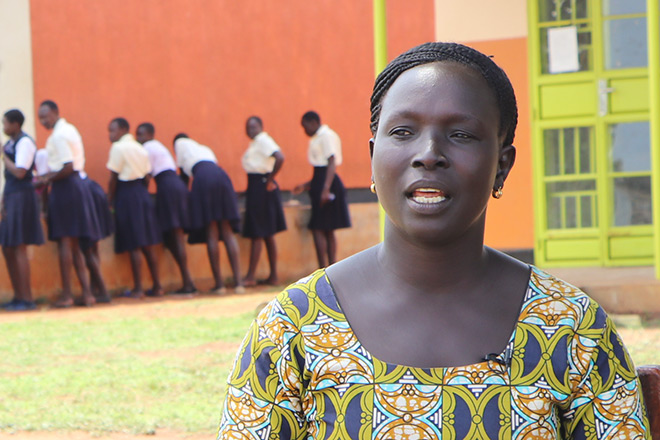 Hygiene-Aufklärung: Portrait einer ugandischen Lehrerin vor einer Mädchengruppe