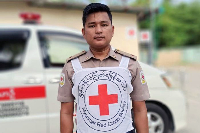 Myanmarischer Helfer mit Rotkreuzleibchen vor Einsatzwagen