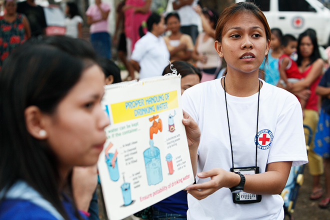 Philippinische Rotkreuz-Helferinnen mit Schild übers Händewaschen 
