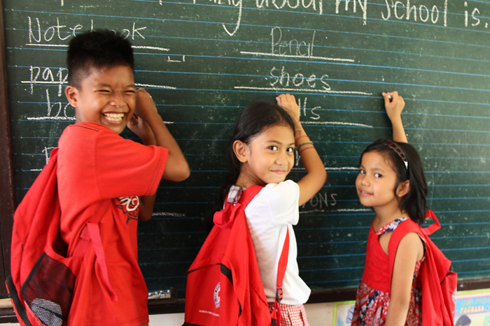 Philippinische Kinder schreiben an eine Tafel und lachen nach dem Wiederaufbau