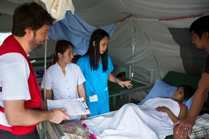 Rotkreuzhelfer am Bett einer philippinischen Patientin in mobiler Gesundheitsstation