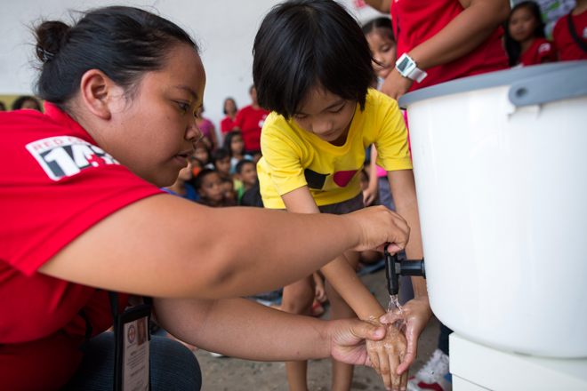 Foto: Eine philippinische Rotkreuzhelferin zeigt einem Kind das Händewaschen
