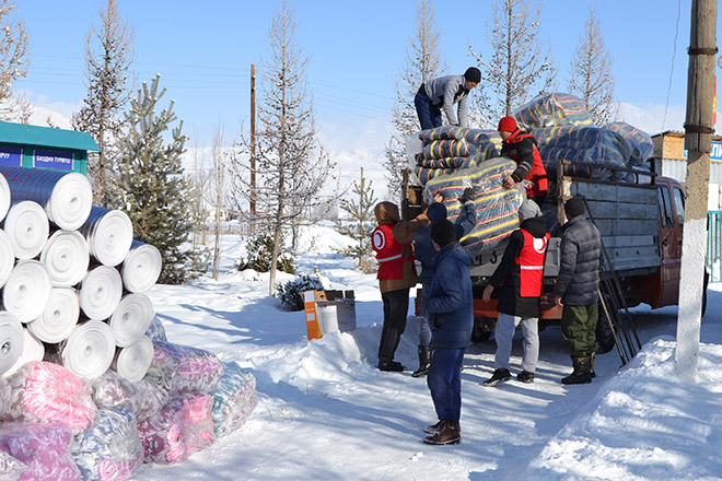 Rothalbmondhelfer laden Winterhilfsgüter von einem Transporter.