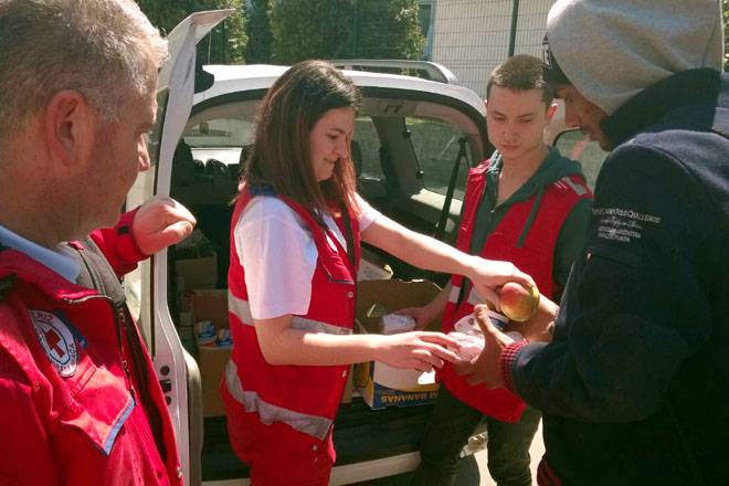 Foto: Rotkreuzhelferin reicht Flüchtlingen Nahrungsmittel (Bosnien-Herzegowina) 