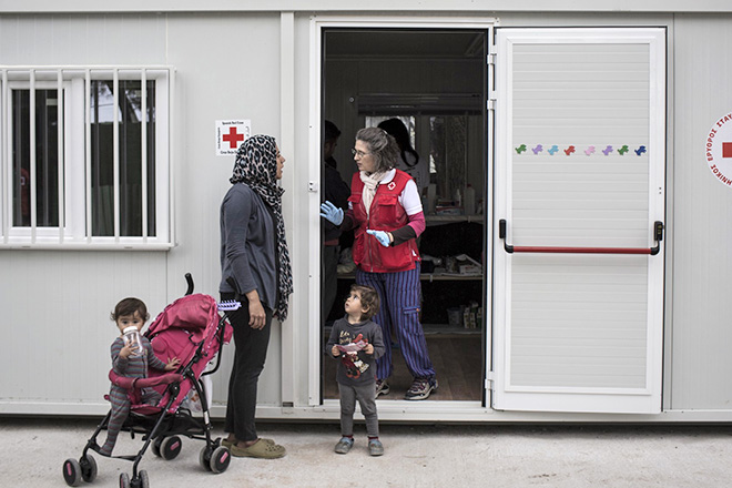 Foto: eine geflüchtete Mutter mit ihren Kindern im Gespräch mit einer Rotkreuzmitarbeiterin in Griechenland