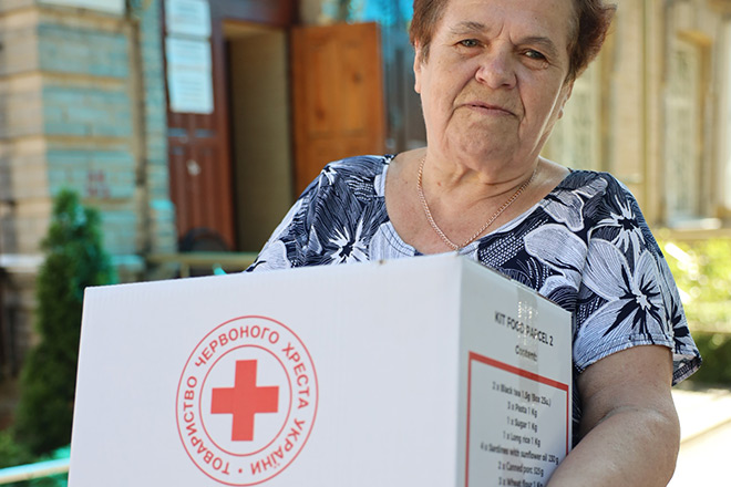 Seniorin mit einem Hilfsgüterkarton im Arm