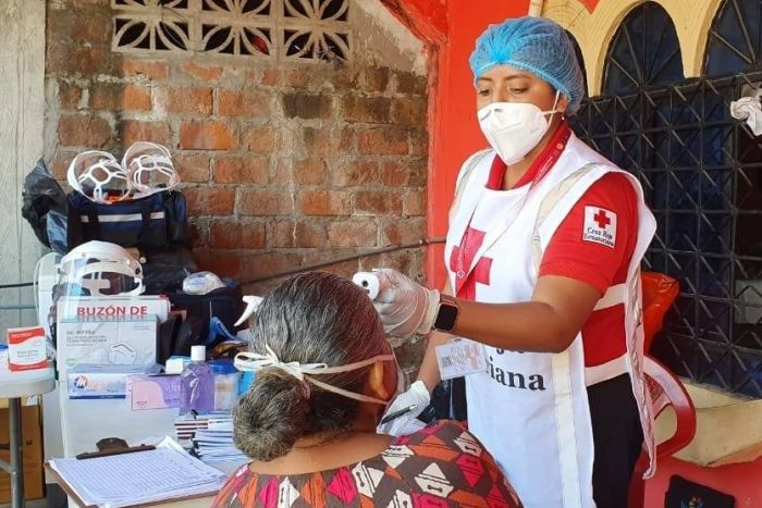 Mitarbeiter des Ecuadorianisches Rotes Kreuz untersucht Frau auf Corona