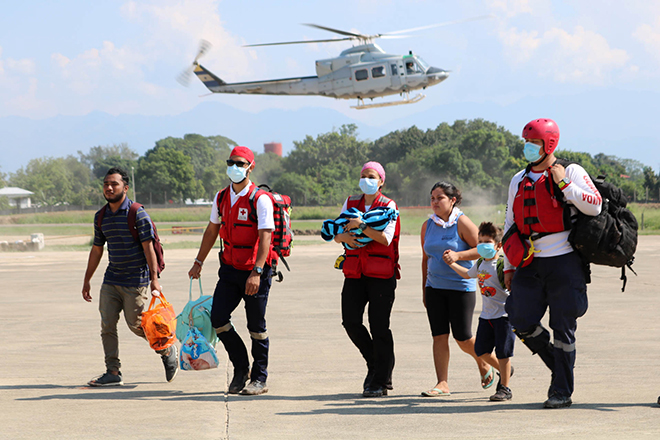 Rotkreuz-Einsatzkräfte helfen bei der Evakuierung in Honduras, darüber ein Hubschrauber