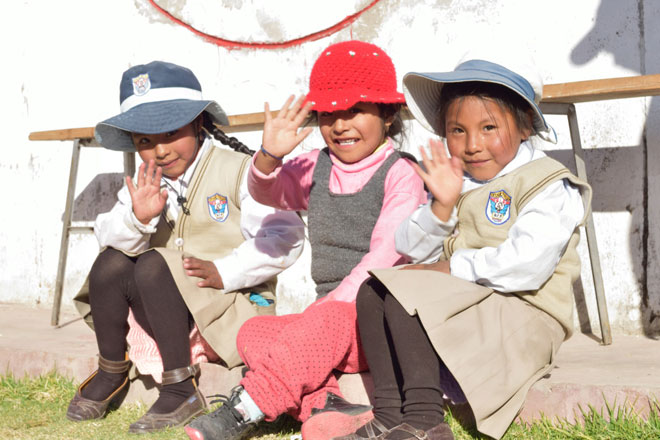 Drei peruanische, kleine Mädchen winken in die Kamera