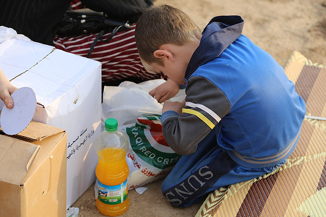 Flüchtlingskind schaut in Hilfspakete.