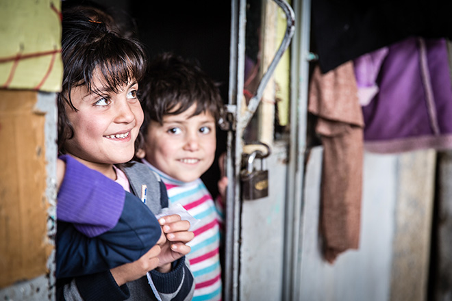 Zwei irakische Kinder schauen lächelnd aus Unterkunft