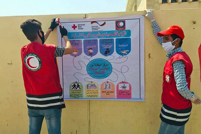 Irakische Rothalbmond-Helfer bringen Plakat an