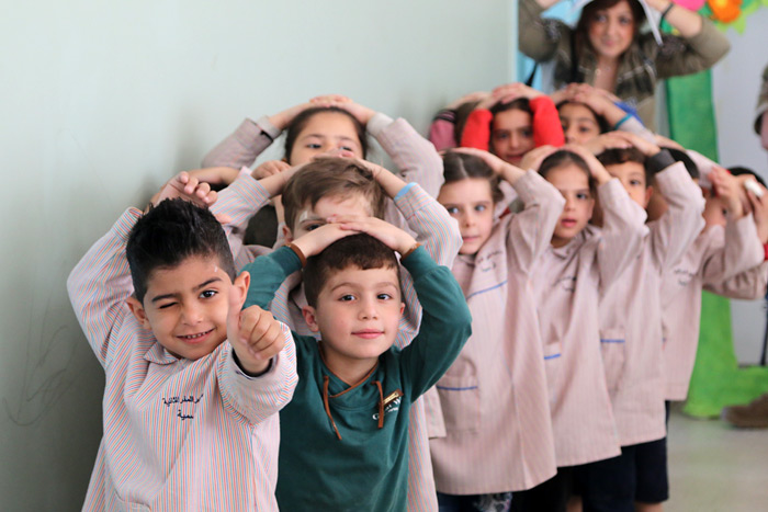 Fotos: Kinder, die hintereinander stehen und die Hände auf dem Kopf haben