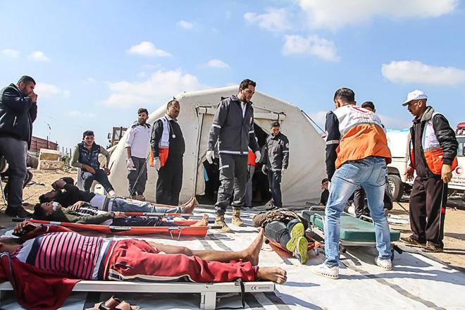 Foto: Verletzte auf Tragen vor einem Zelt in Palästina