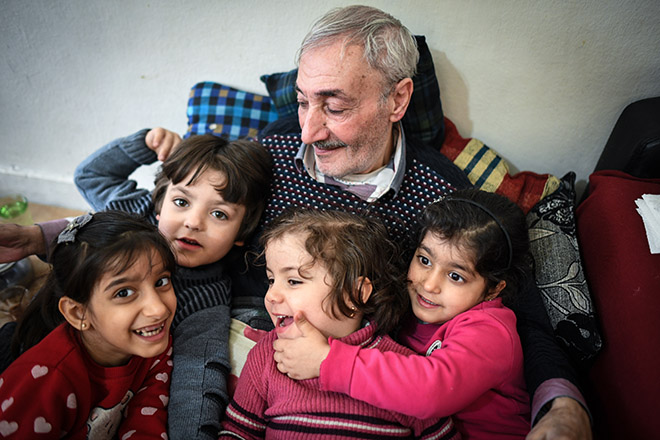 Ein syrischer Großvater lacht mit seinen Enkelinnen