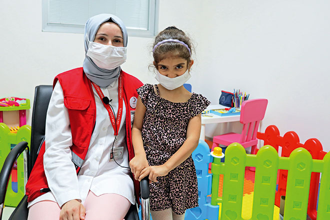 Türkische Rothalbmondmitarbeiterin mit Mädchen in Therapieraum