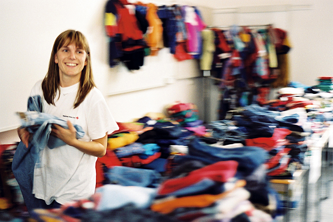 DRK Helferin mit gespendeter Kleidung in einer Kleiderkammer