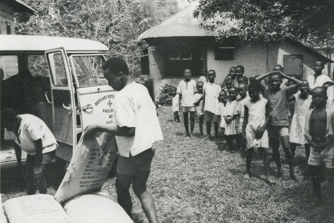 Foto: Nigerianischer Helfer lädt Säcke in einen DRK-Transporter