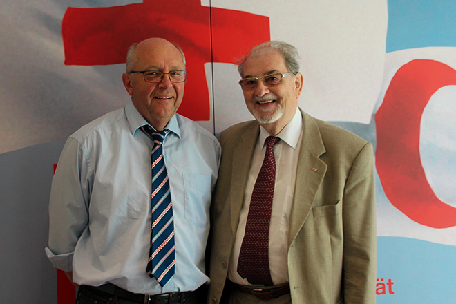 Thomas Klemp und Christoph Brückner vor einer internationalen Rotkreuz-Fahne
