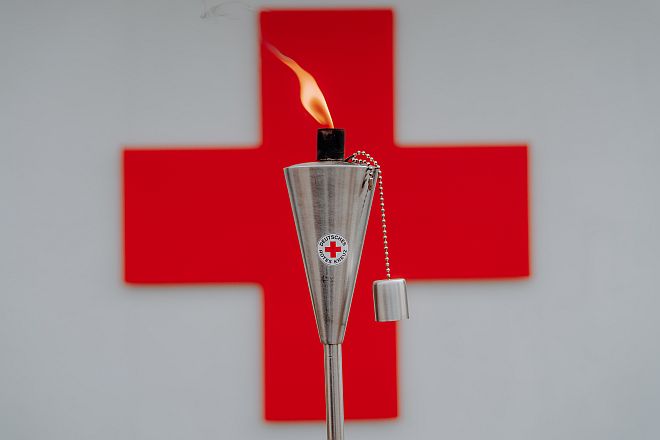 DRK-Fackel vor Rotem Kreuz Logo