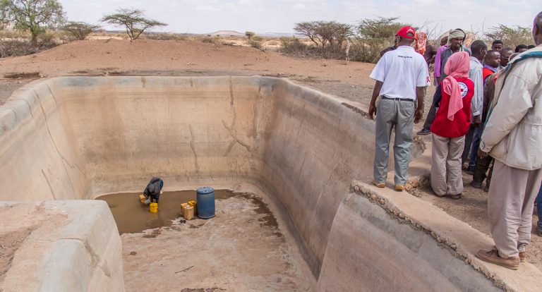 Frau schöpft Wasser in fast leerem Wasserspeicher