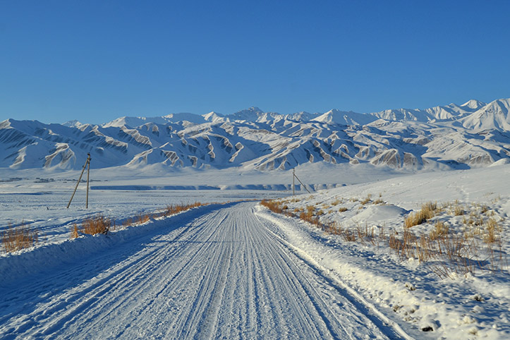 verschneite Straße vor kirgisischen Bergen