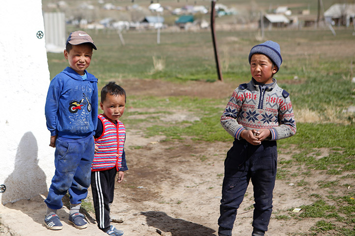 Drei kirgisische Kinder auf Wiese