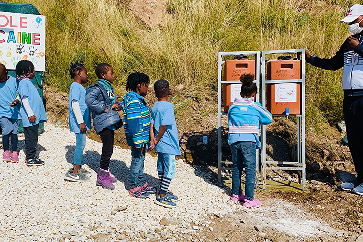 Kinder stehen Schlange vor Handwaschstation